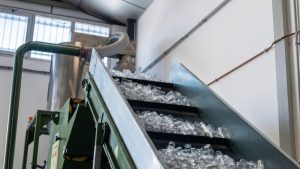 Cinta transportadora introduciendo material en la maquinaria industrial para la producción de plástico reciclado en las instalaciones de Plasnovo.